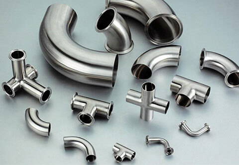 A group of stainless steel pipe fittings including elbows, tees, and couplings