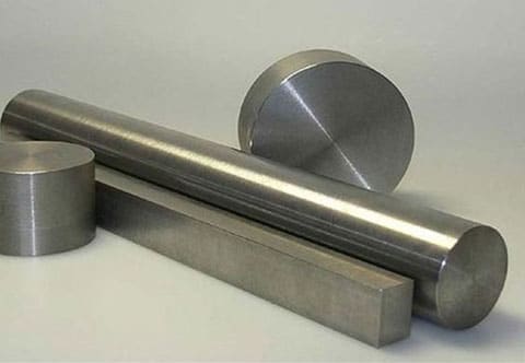A photo showing four metallic objects: two cylindrical rods of different diameters, one short cylindrical piece, and one rectangular bar