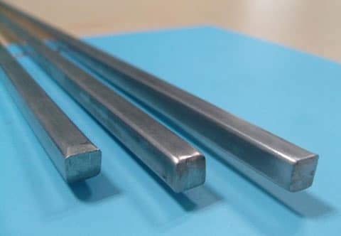 hree metal bars of varying thicknesses are aligned parallel on a blue surface.